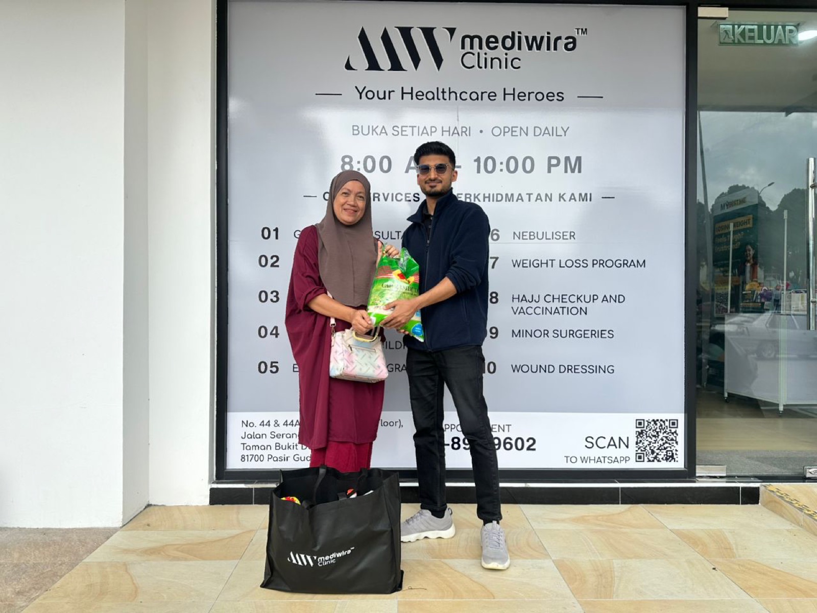A resident receiving rice and a Mediwira grocery bag at the clinic entrance
