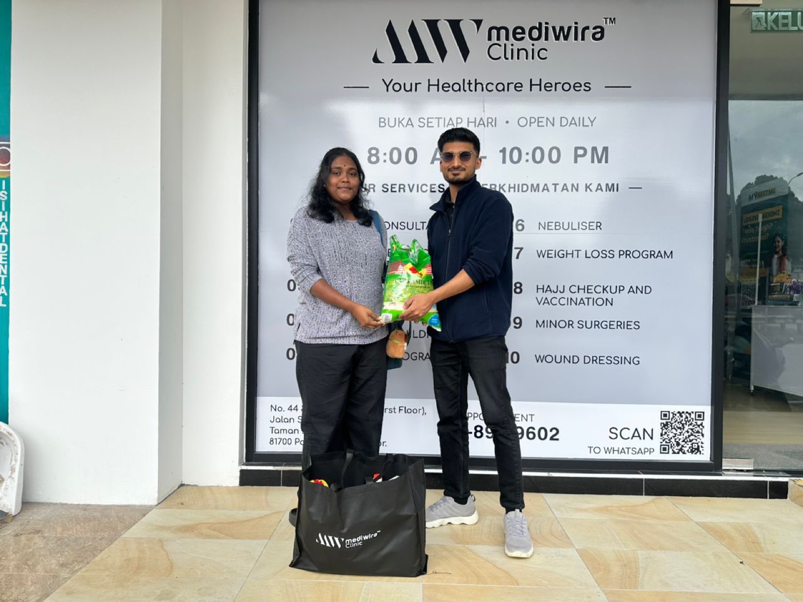 A resident collecting a grocery pack from a Mediwira team member outside the clinic