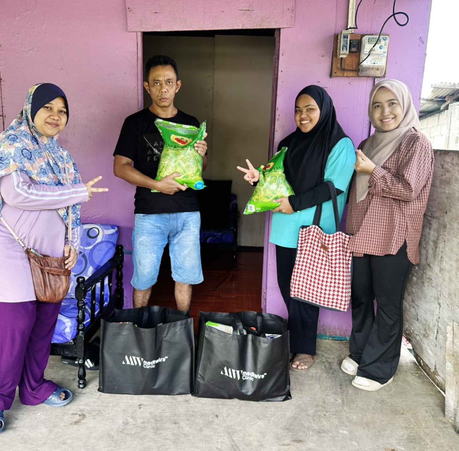 Mediwira staff and volunteers delivering grocery bags to a family at home