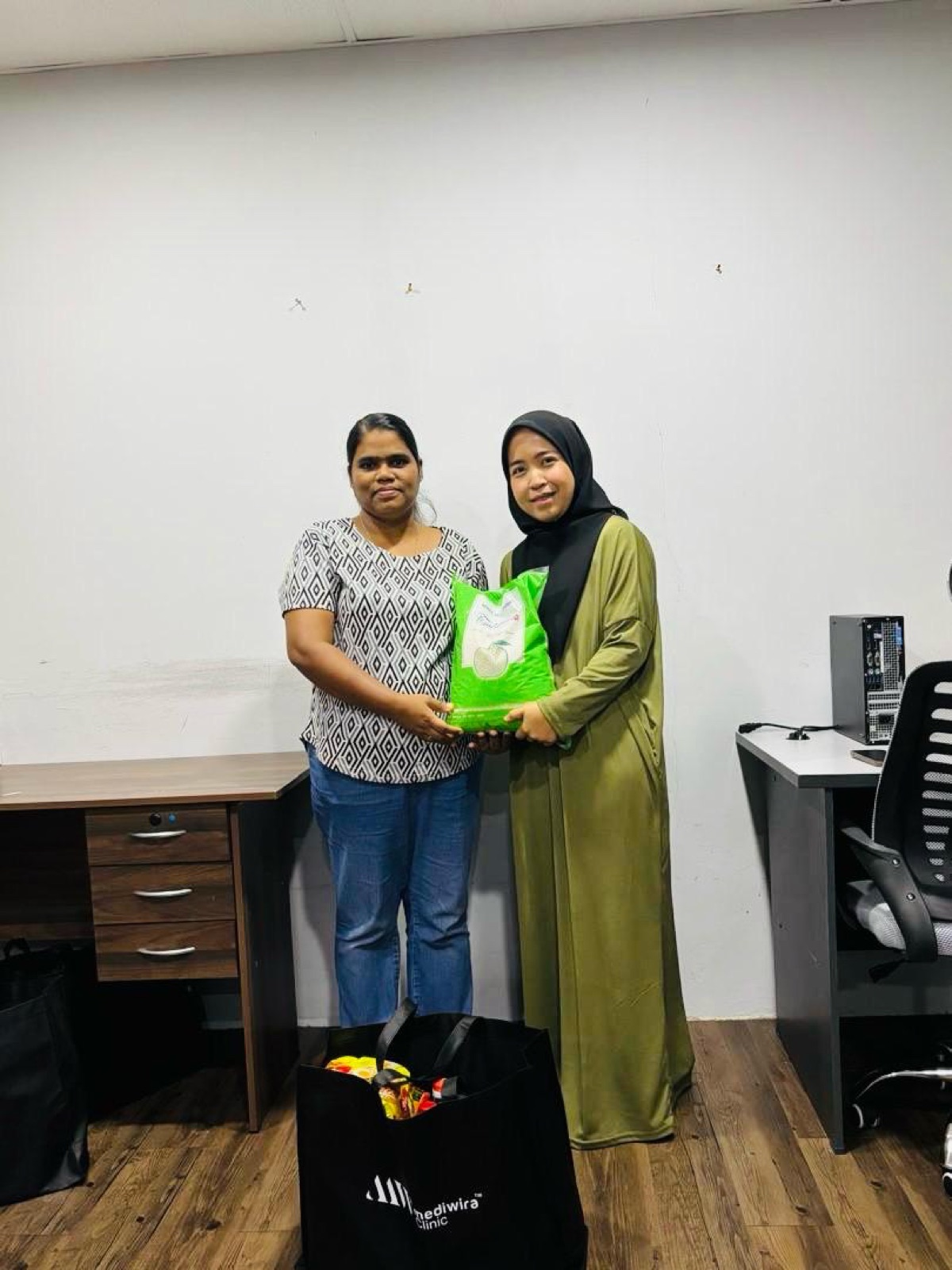 A recipient collecting rice and a grocery bag from Mediwira staff