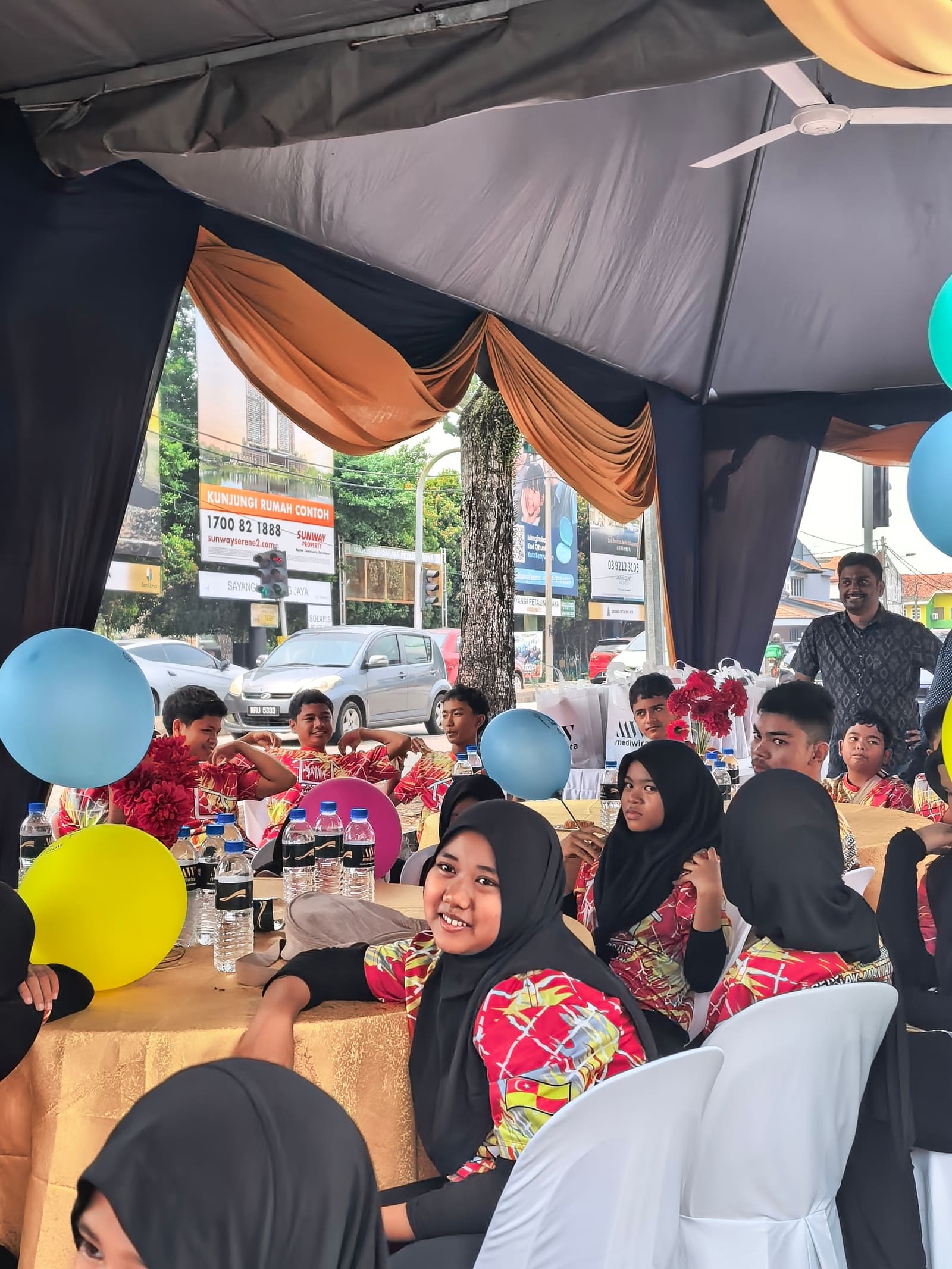 Guests seated under the marquee with balloons overhead and goodie bags on the tables
